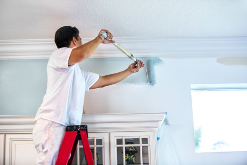 man on ladder painting wall blue